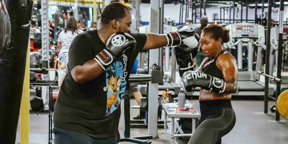 Personal trainer sparring with a client using gloves in a gym setting