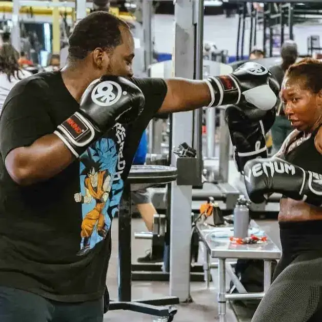 Personal Training Session Personal trainer sparring with a client using gloves in a gym setting