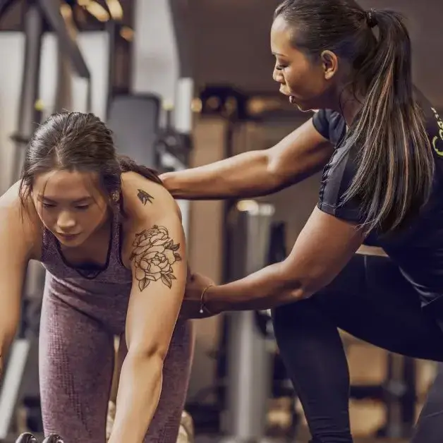 Personal Trainer Assisting Client During Strength Training Personal trainer providing guidance to a client during a strength training workout