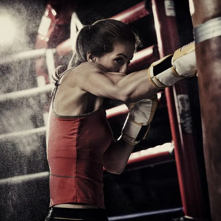 Woman Practicing Heavy Bag Punches in a Boxing Gym Female boxer performing heavy bag work during a training session