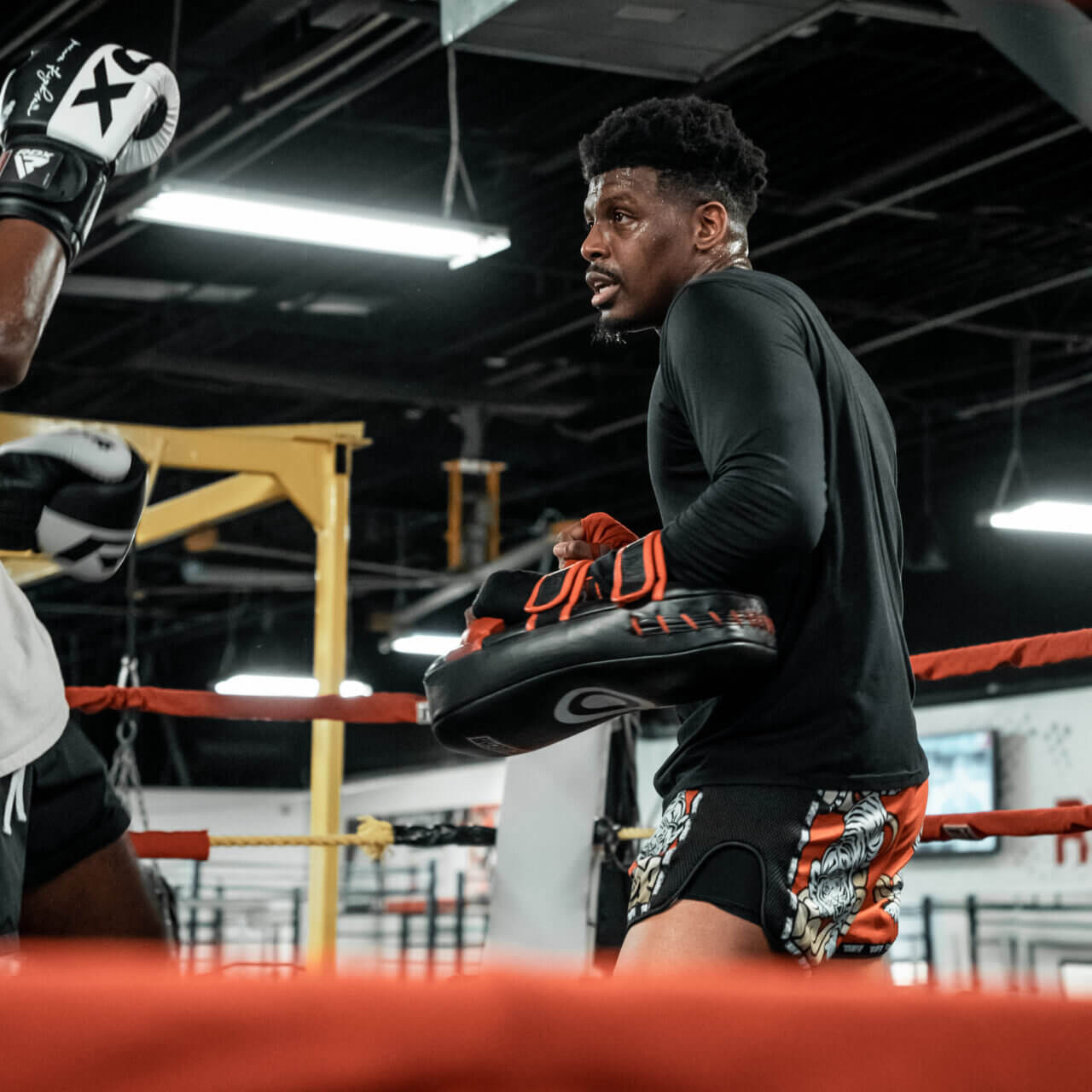 Muay Thai Training in the Gym Male Muay Thai trainer holding pads during a training session.